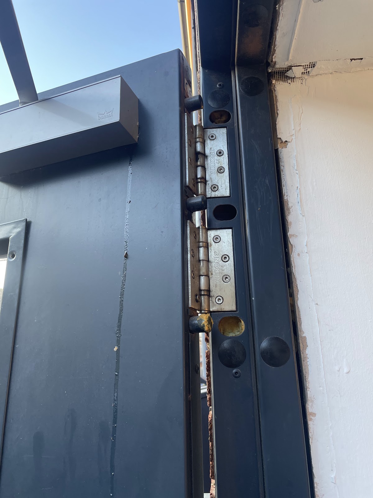 Overhead door closer and heavy duty hinges on a commercial entrance door