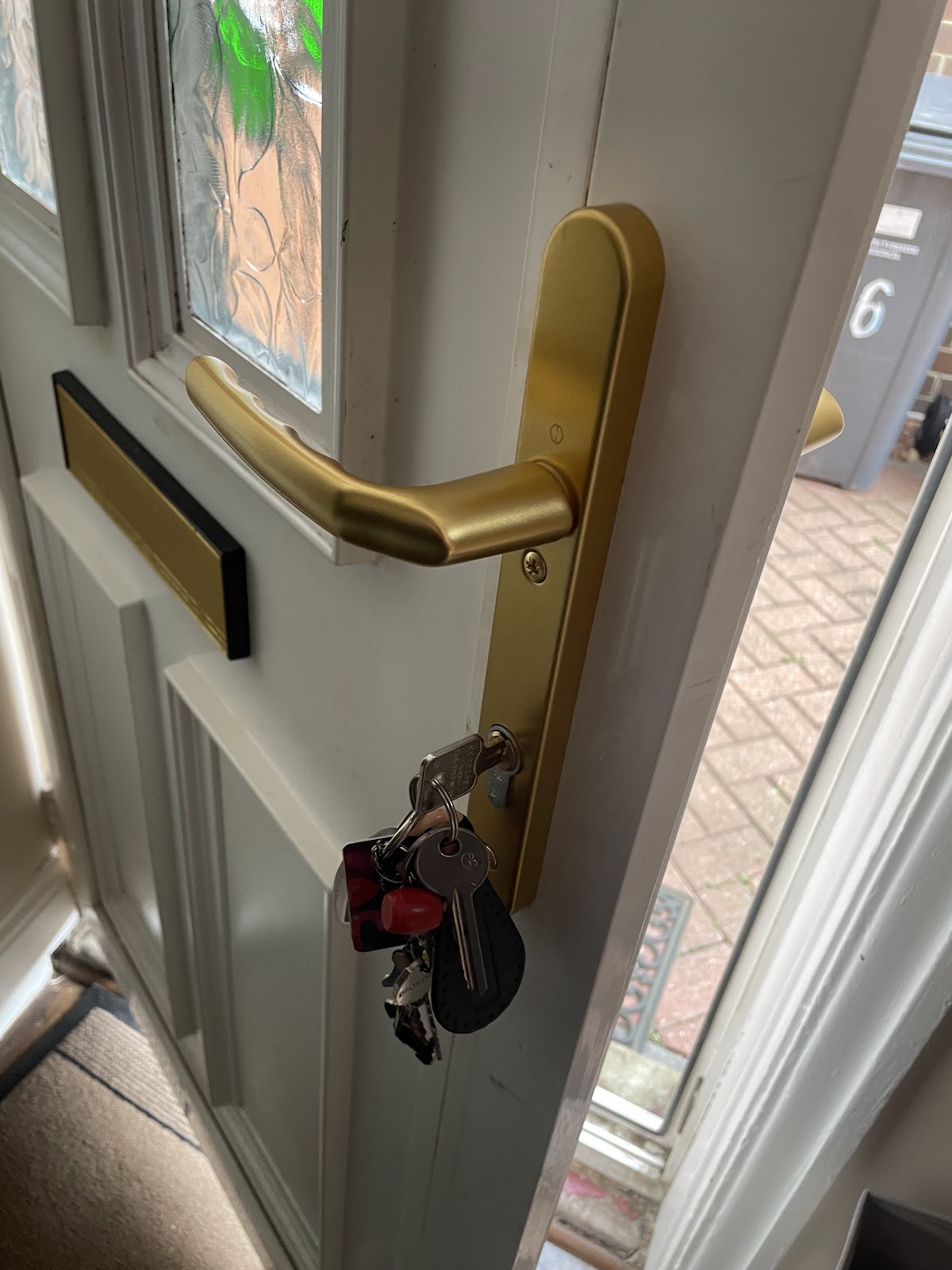 New lock and gold handle fitted to a white composite front door, keys in the barrel